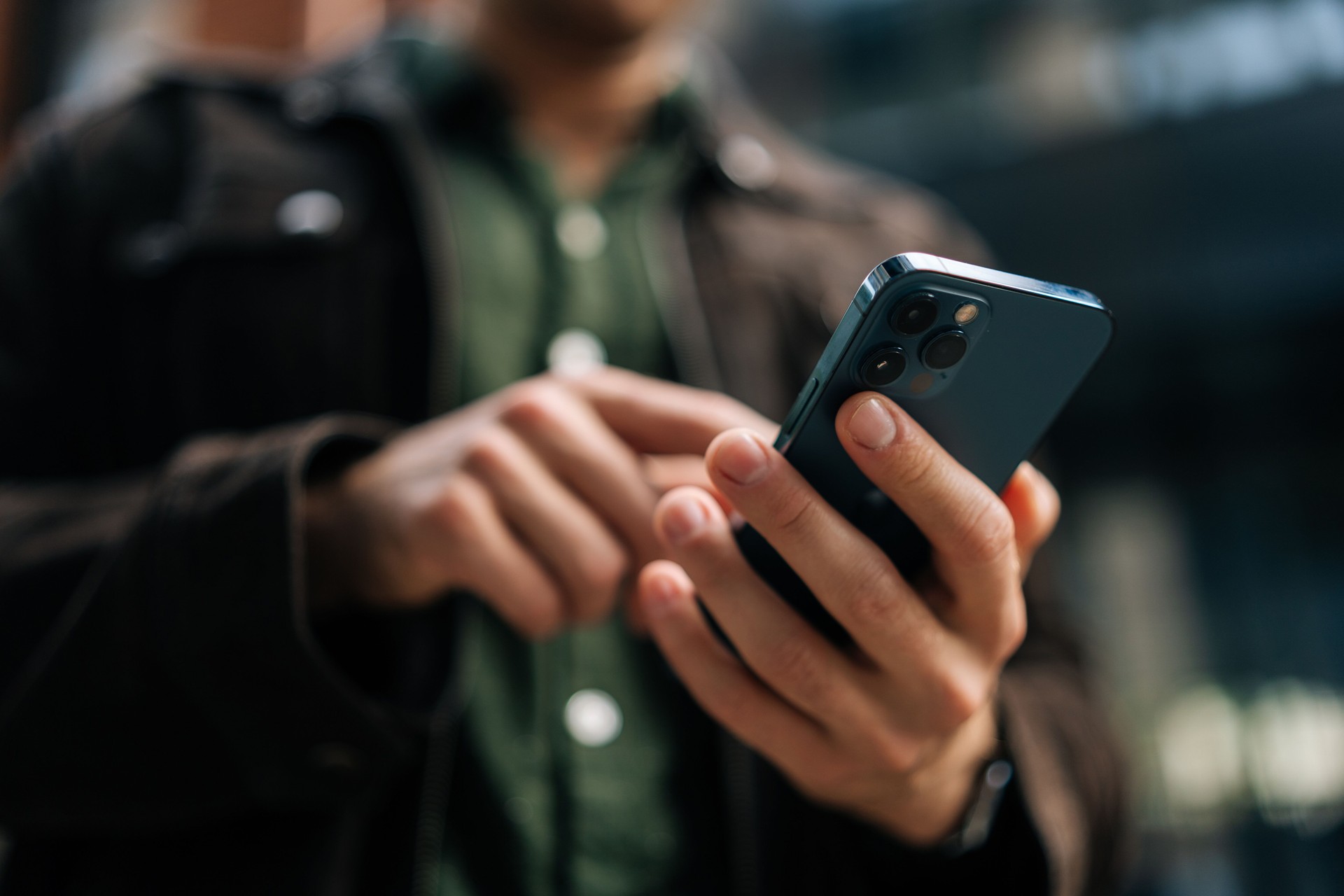 Gros plan des mains d’un homme méconnaissable tenant et utilisant un smartphone debout dans la rue de la ville, naviguant sur Internet, vérifiant les médias sociaux, utilisant une application mobile.