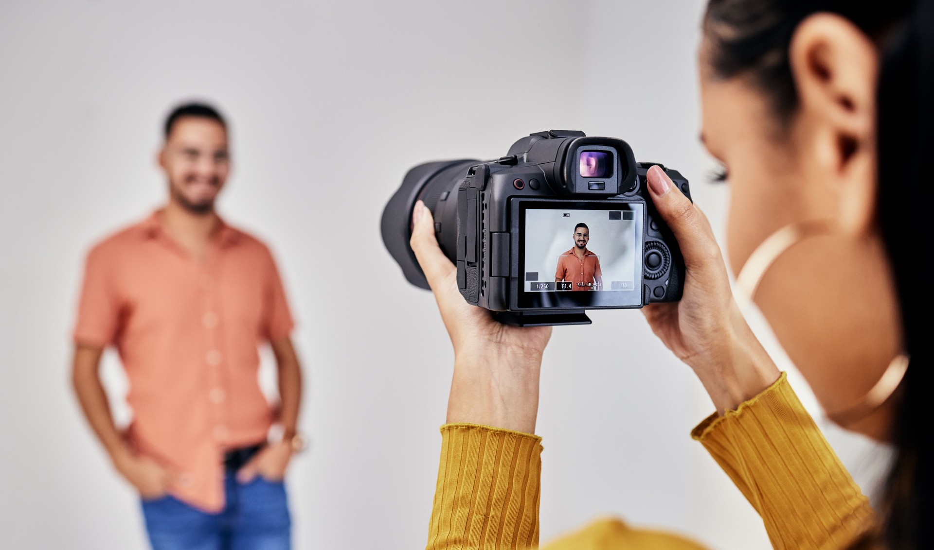 Femme, photographie de studio et appareil photo avec homme, modèle et vision pour la mode, magazine ou designer. Fille photographe, focus et espace de travail avec arrière-plan, idées et photoshoot pour le blog de design de vêtements