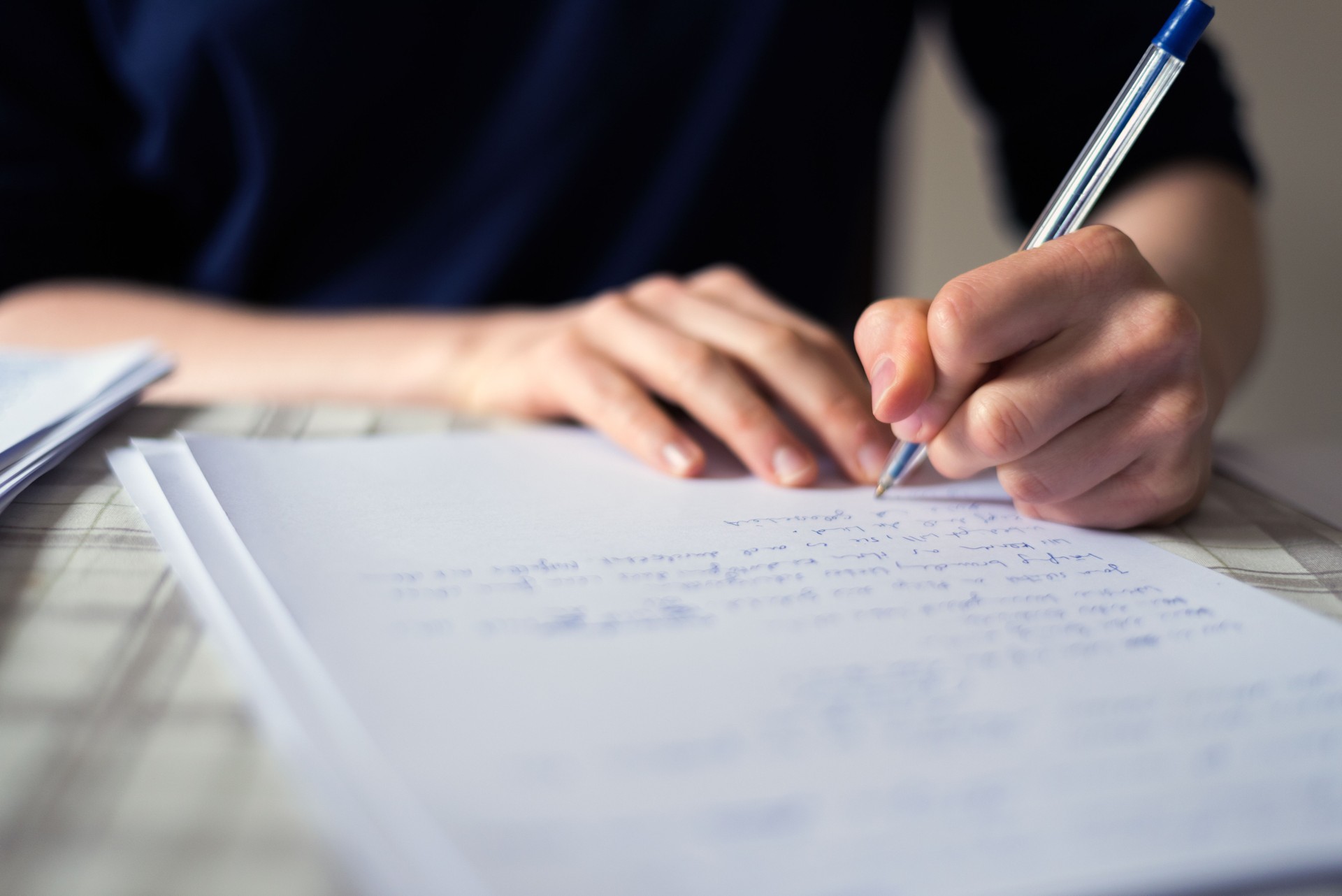 Main qui écrit le texte sur fond de papier avec l’espace de copie